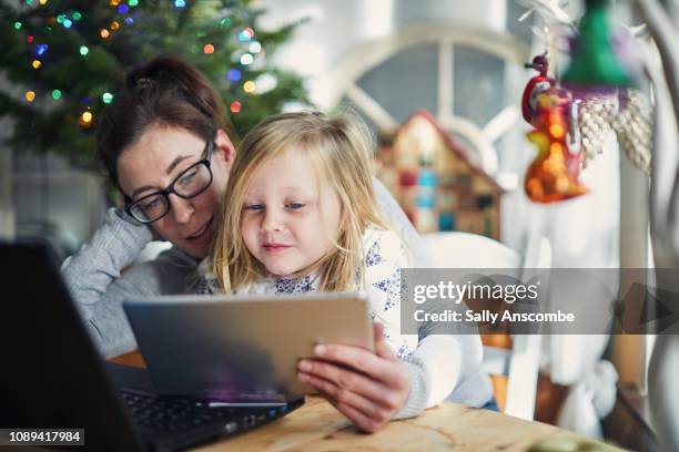 woman and child christmas shopping online - christmas shopping stock pictures, royalty-free photos & images