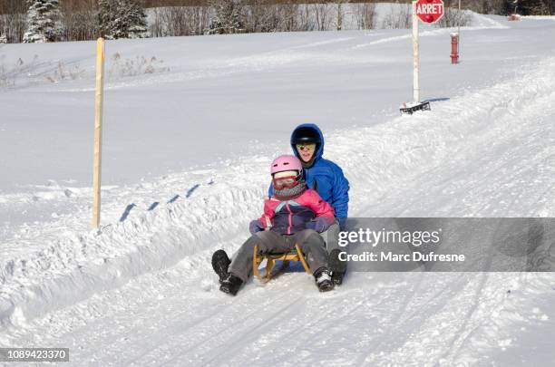 mother and daughter sliding down on an austrian toboggan during winter day - luge stock pictures, royalty-free photos & images