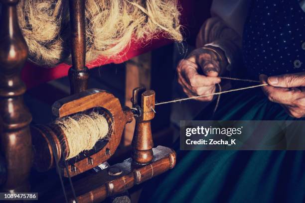 alte frau spinnen von wolle mit traditionellen spinnrad - spinnrad stock-fotos und bilder