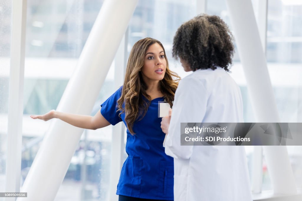 Upset female healthcare professional talks with colleage