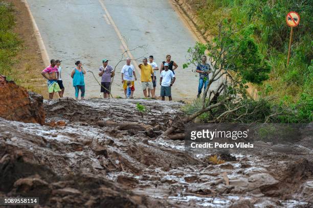 People watch a road buried in mining waste a day after the collapse of a dam from an iron-ore mine belonging to Brazil's mining company Vale, in...