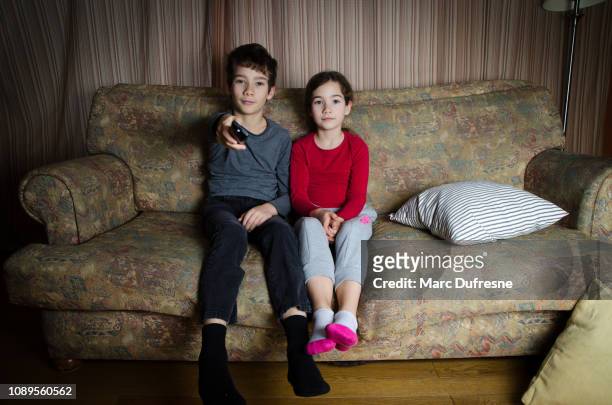 zwei kinder genießen tv sitzen auf der couch im wohnzimmer - kid watching tv stock-fotos und bilder
