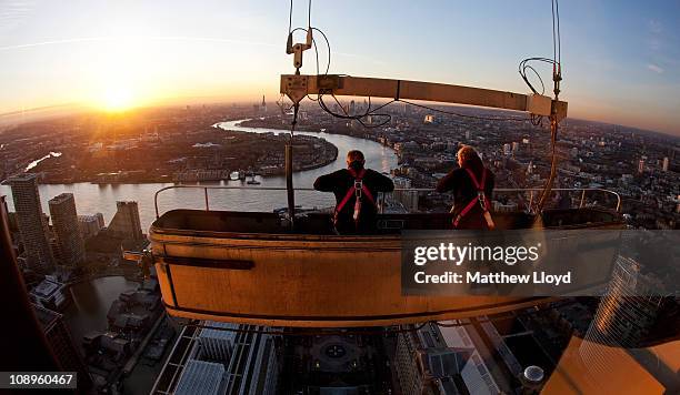 Window cleaners Lee Mason and Paul Wright pause for a break in their cleaning gondola outside the 50th floor of the One Canada Square skyscraper on...