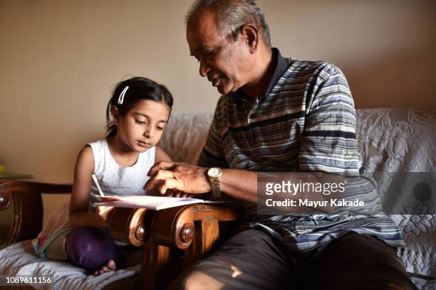 Young girl doing homework with grandfather