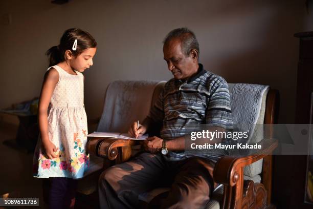 young girl doing homework with grandfather - granddaughter stock pictures, royalty-free photos & images