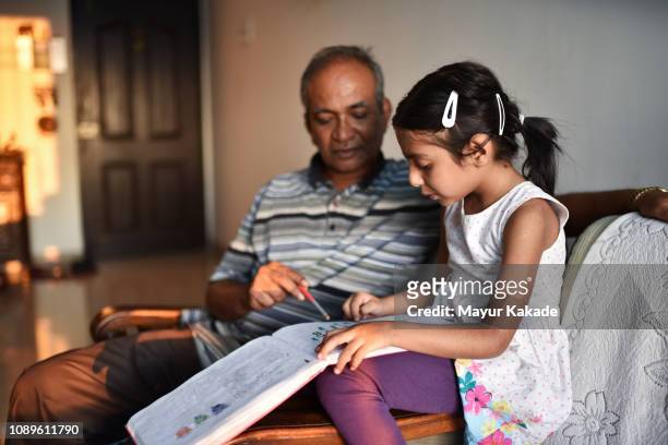 young girl doing homework with grandfather - granddaughter stock pictures, royalty-free photos & images