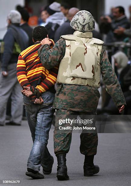 An Egyptian army soldier escorts an accused thief near parliament on February 10, 2011 in Cairo, Egypt. Thousands of workers from various unions...