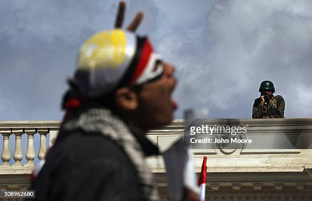 An anti-government protester chants as an Egyptian army soldier watches from the roof of parliament on February 10, 2011 in Cairo, Egypt. Thousands...