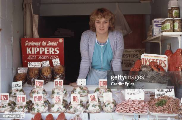 Woman on her stall which is selling fresh kippers oysters, shrimps and prawns in Scarborough, Yorkshire, September 1982.
