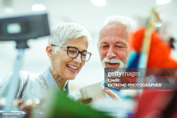 senior couple shopping for a small white leather wallet together in a bags and accessories store - old man wallet stock pictures, royalty-free photos & images