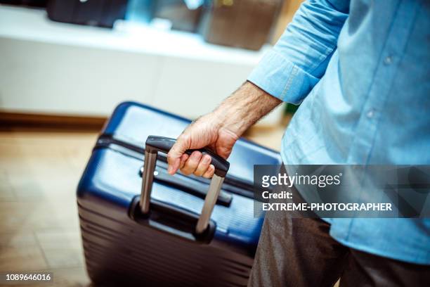 maleta de viaje azul marino grande por una persona irreconocible en una tienda de bolsos y accesorios - manilla fotografías e imágenes de stock