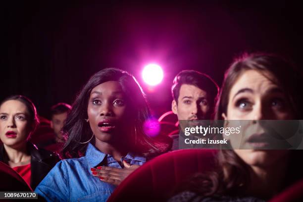 young people watching thriller movie in the cinema - movie audience stock pictures, royalty-free photos & images