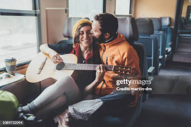 couple playing the guitar in train - martin guitar stock pictures, royalty-free photos & images