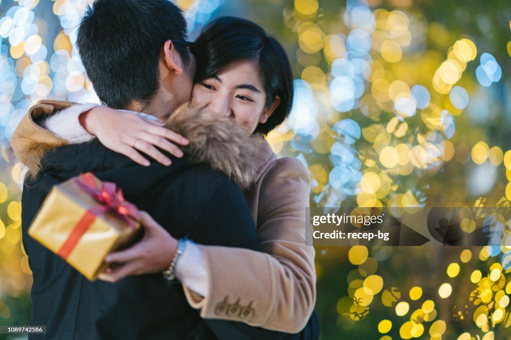 Namorada feliz, abraçando o namorado, mantendo a caixa de presente