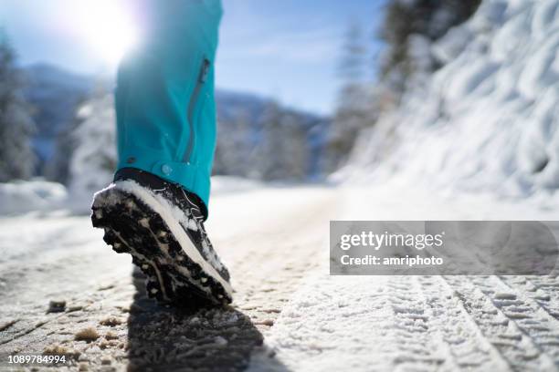 closeup sports shoe female leg walking on winter country road backlight sunlight - slush stock pictures, royalty-free photos & images