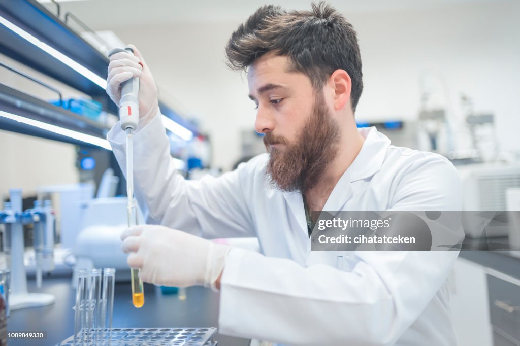 Young male tech or scientist loads sample with automatic pipette