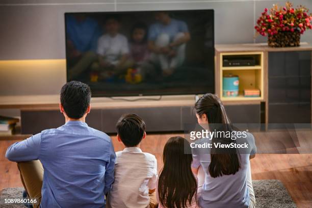 happy families are watching tv - family watching tv from behind stock pictures, royalty-free photos & images