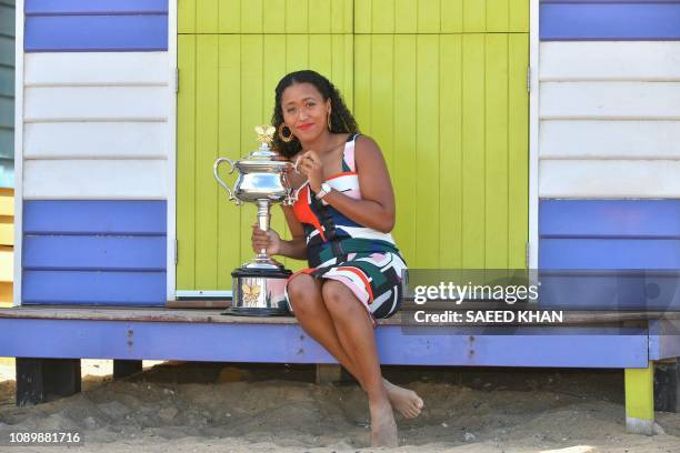 Japan's Naomi Osaka poses for photographs with the championship trophy at the Brighton Beach in Melbourne on January 27 a day after her victory...
