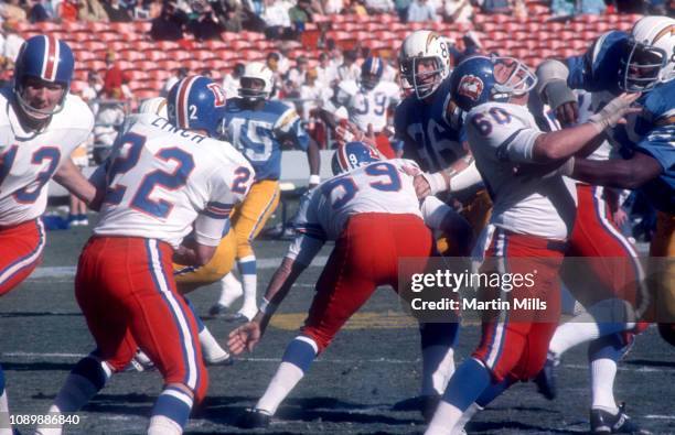 Fran Lynch of the Denver Broncos gets the hand-off as his teammate Larry Kaminski blocks Pete Barnes of the San Diego Chargers during an NFL game on...