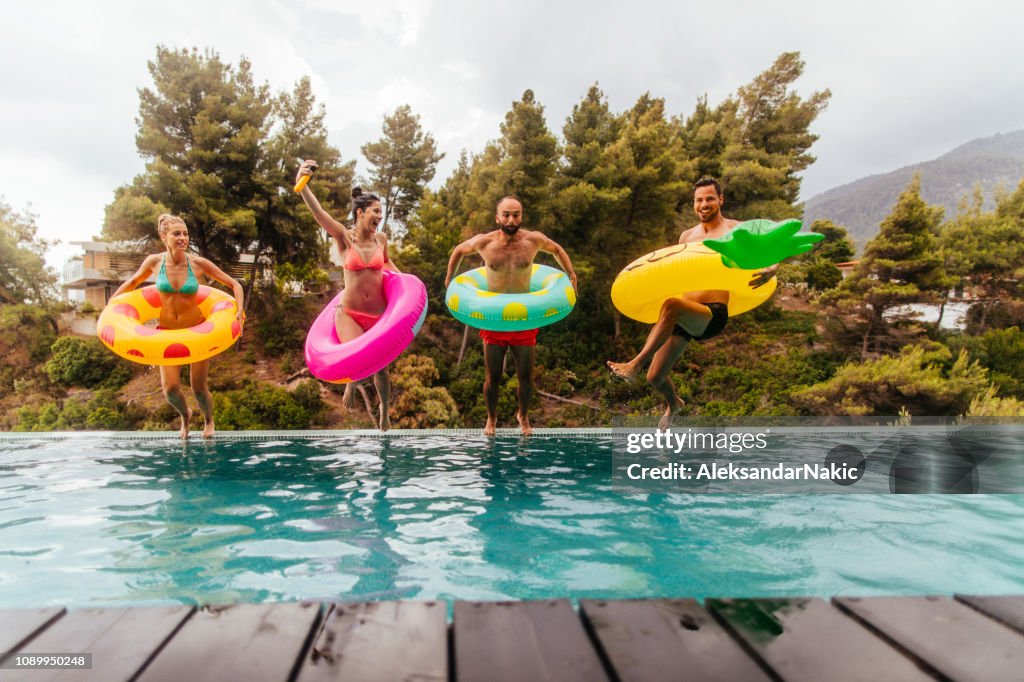 Amigos están saltando a la piscina