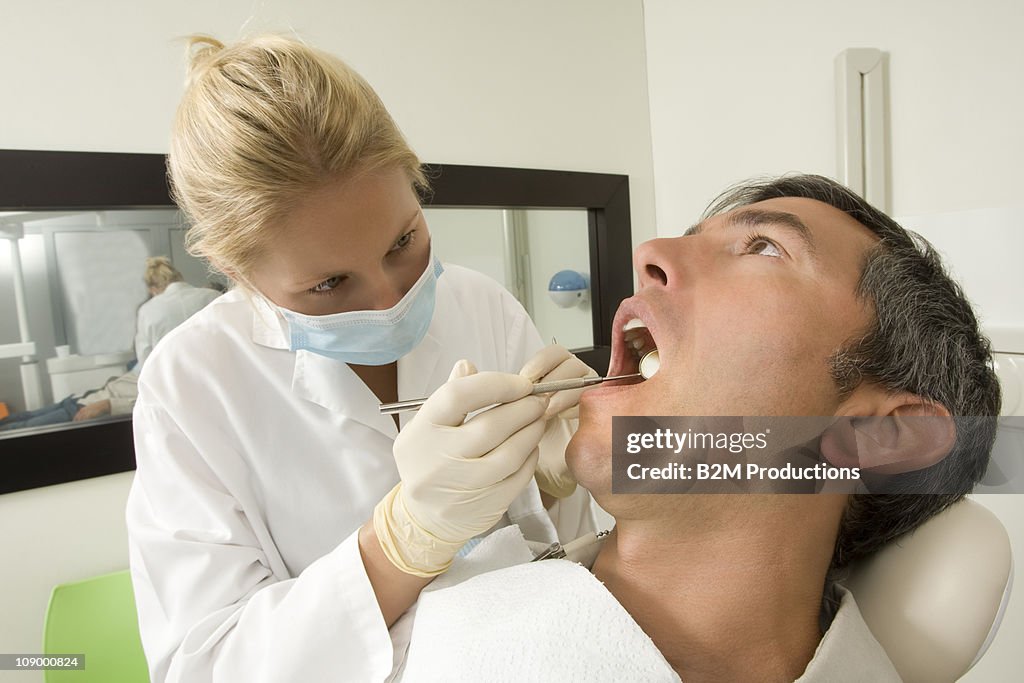 Female dentist examining man
