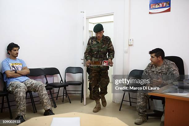 An Afghan National Army soldier carries some cups of tea into a room where US army SSG Ryan Hern, 27 from Georgia, Alpha Company 1/121 Infantry ,...