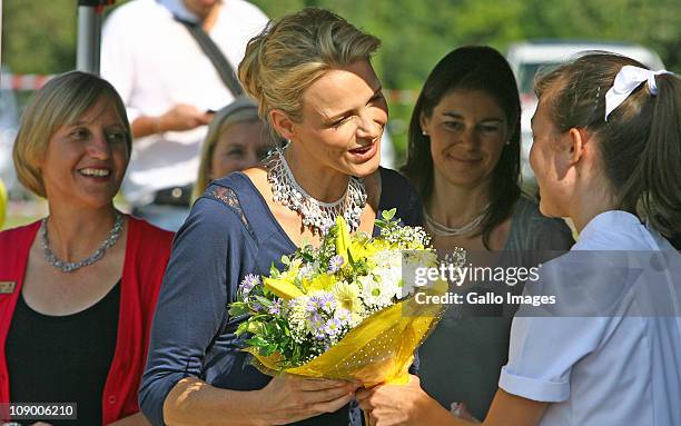 Former South African Olympic swimmer and future Princess of Monaco Charlene Wittstock receives flowers from head girl Bianca Wittig during a visit St...