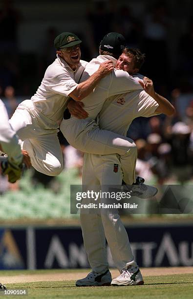 Michael Slater joins Glenn McGrath of Australia as he congratulates Justin Langer after he caught West Indies captain Jimmy Adams first ball for...