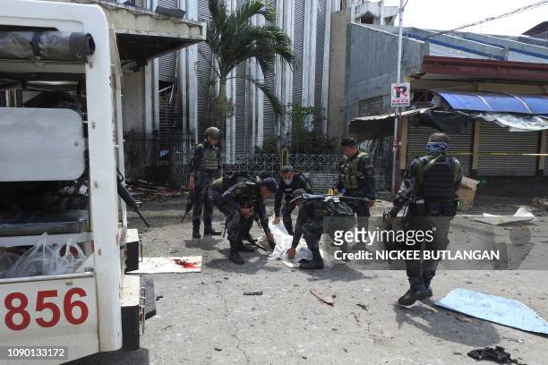 Philippine security personnel carry a body bag containing the remains of a blast victim after two bombs exploded at a church in Jolo, Sulu province...