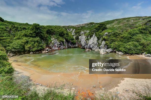 gulpiyuri beach. a beach linked to the sea through an underground tunnel. it is a flooded sinkhole with an inland beach - llanes stock-fotos und bilder