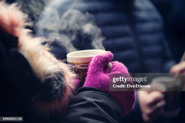 close up of adult holding a mug of hot glühwein at a german christmas market - glühwein stock-fotos und bilder