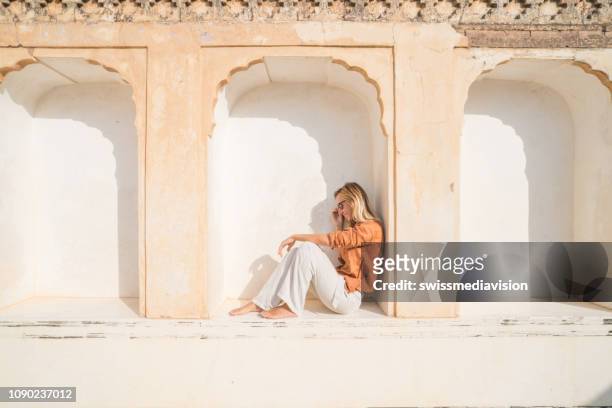 young woman traveling in india visiting temple sitting on window contemplating the architecture. people travel discovery asia concept. - jaipur city palace stock pictures, royalty-free photos & images