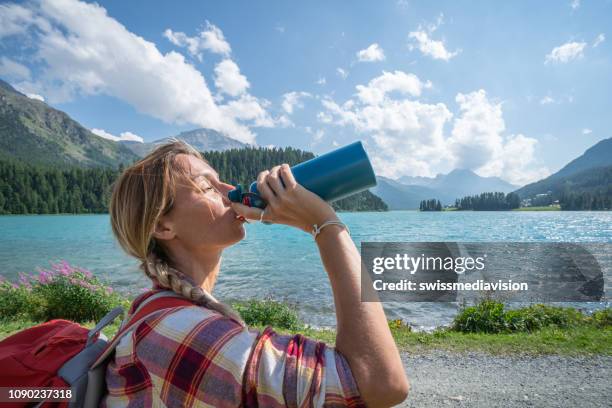 hiker woman drinking on mountain lake trail from water bottle - gourd stock pictures, royalty-free photos & images