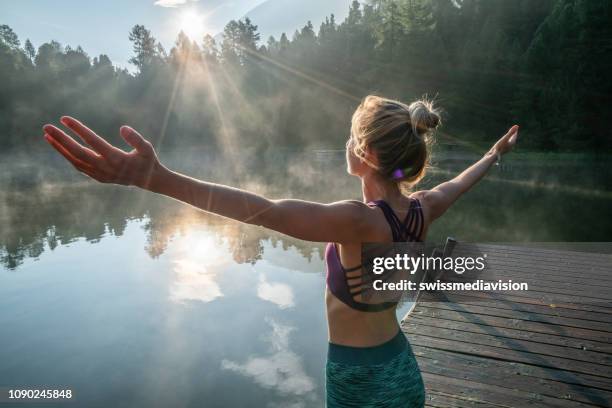 mujer practicando posturas de yoga en la naturaleza, embarcadero del lago - preocupación por el cuerpo fotografías e imágenes de stock