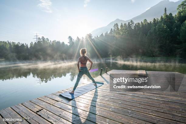 woman practicing yoga poses in nature, lake pier - outdoor yoga stock pictures, royalty-free photos & images