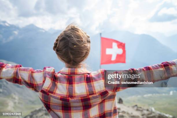 vrouw bovenop de berg permanent armen gestrekt; zwitserse vlag in de zwitserse alpen - swiss flag stockfoto's en -beelden