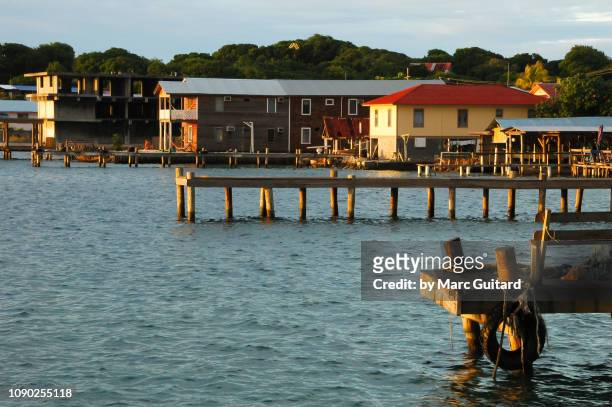 piers and village on utila at sunset, bay islands, honduras - utila honduras stock pictures, royalty-free photos & images
