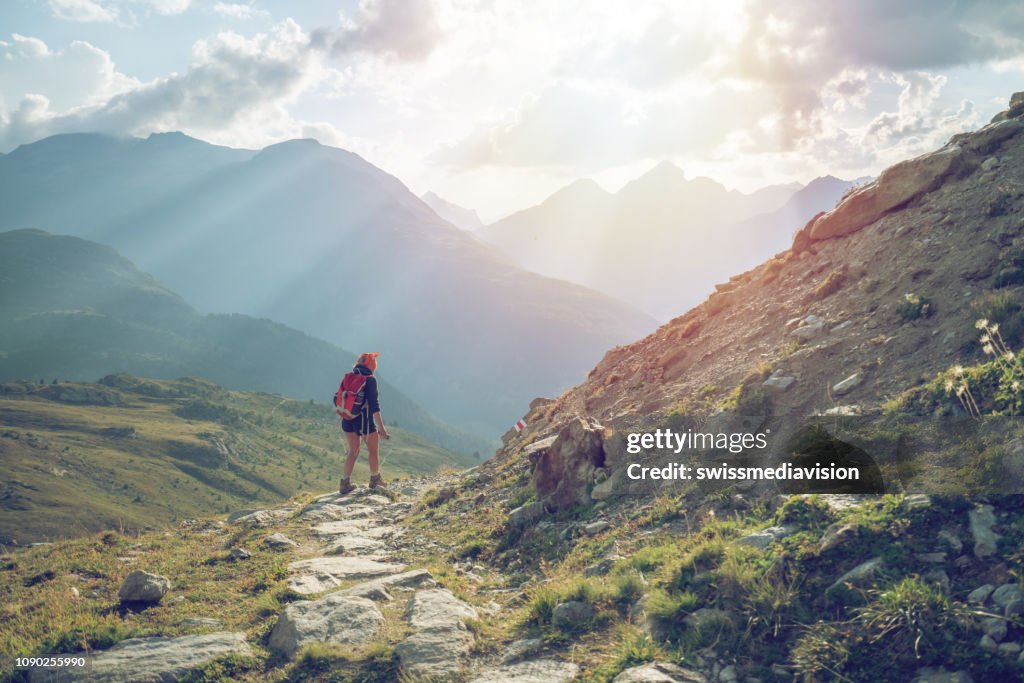 Junge Frau wandert und wandert auf Bergweg am Sonnenuntergang-Schweiz