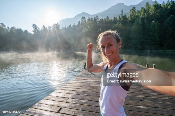 jeune femme sportive prenant le selfie après le jogging de matin dans la nature, tourné par le lac au lever du soleil - after run photos et images de collection