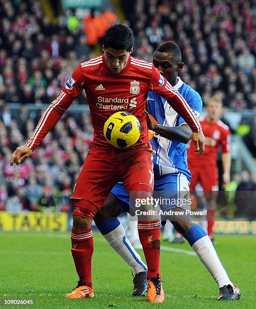Luis Suarez of Liverpool shields the ball from Steve Gohouri of Wigan during the Barclays Premier League match between Liverpool and Wigan Athletic...