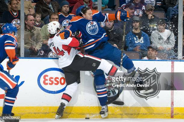 Chris Campoli of the Ottawa Senators takes a hard hit from Kurtis Foster of the Edmonton Oilers at Rexall Place on February 12, 2011 in Edmonton,...