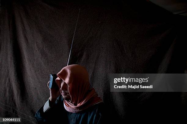 An Afghan man holds a radio to his ear as families, displaced by conflict, carry on their lives in makeshift tents in an extremely cold climate, on...