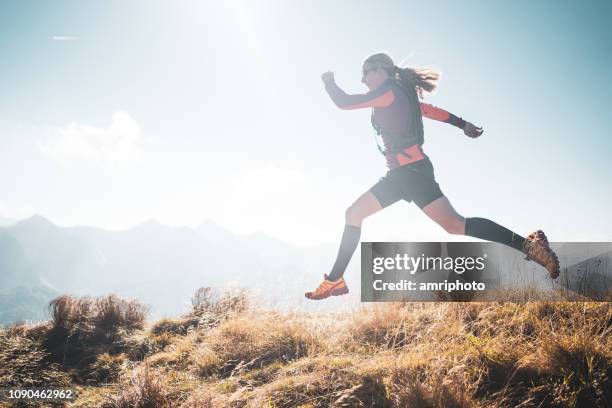 vitality freedom cross country running sporty woman jumping big step side view in mountains - compression socks stock pictures, royalty-free photos & images