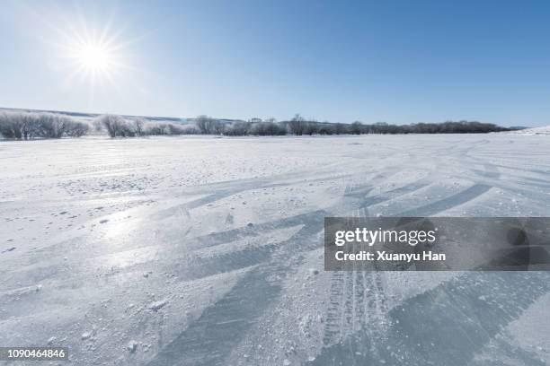 vehicle tracks through thick layer of ice, with blue sky - neige épaisse photos et images de collection