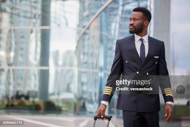 black person pilot walking at the airport - airline pilot imagens e fotografias de stock