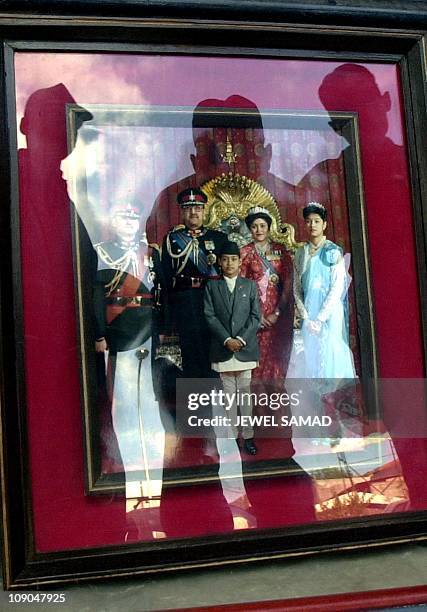 Nepalese security personnel, reflected on the photograph, look at a photograph of the Nepalese Royal family members who died in the palace massacre...