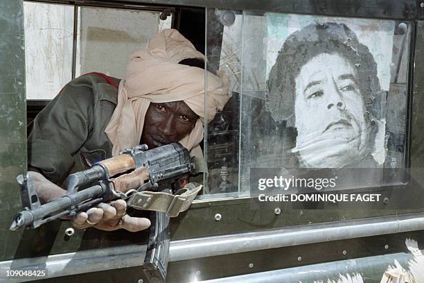 Soldier poses near a portrait of Muammar Kadhafi in a libyan truck gave up by Libyan soldiers on April 09, 1987 in Faya Largeau, after the defeat of...