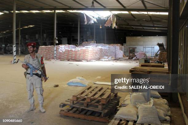 Soldier with a military coalition in Yemen backed by Saudi Arabia and the United Arab Emirates stands guard at a damaged warehouse of Yemen's Red sea...