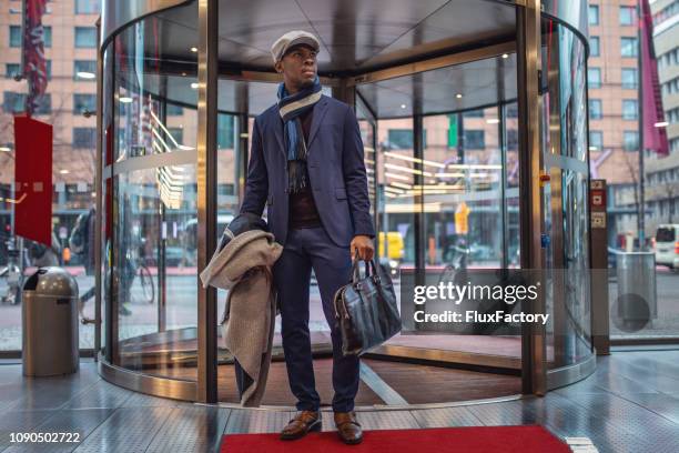 handsome businessman entering the mall through a revolving door - revolving door stock pictures, royalty-free photos & images