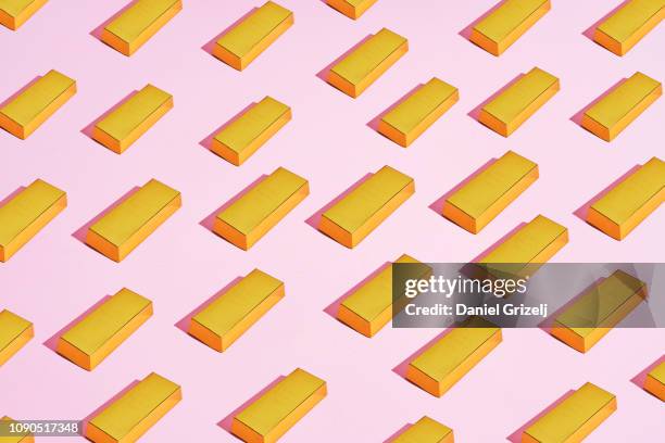 multiple gold bars placed in a pattern on a colored background - gold bars stock-fotos und bilder